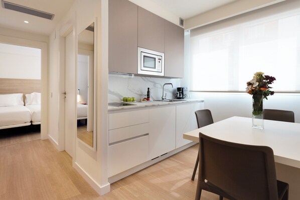 Una habitación de hotel moderna con kitchenette, comedor y cama.