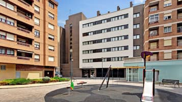 Un patio con juegos infantiles, rodeado de edificios residenciales de varios pisos.