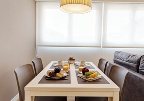 A dining table with breakfast items, a bowl of fruit, and a coffee cup. - Sercotel Logroño Suites (Logroño)