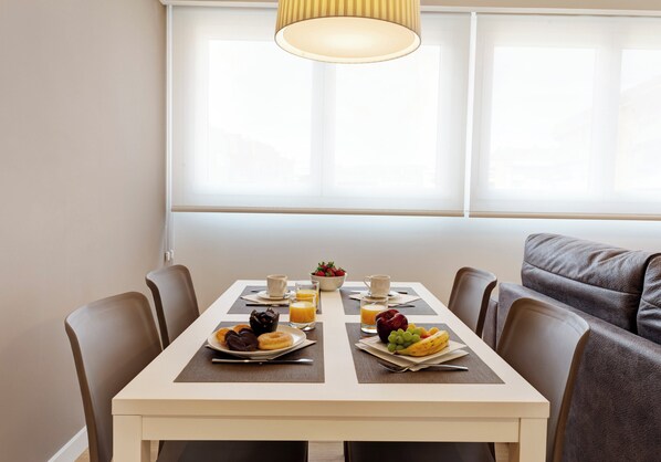 A dining table with breakfast items, a bowl of fruit, and a coffee cup.