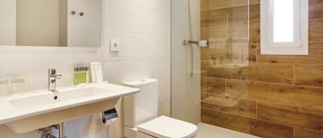 Un baño moderno con lavamanos, inodoro y ducha blancos.