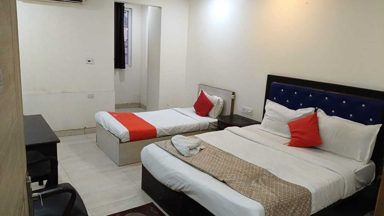 A hotel room with two beds, each with a headboard, a desk, and a chair.