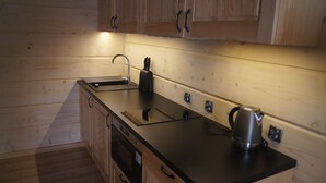 A compact kitchen with wooden cabinets, a black countertop, a kettle, and a toaster. - Apart Orkana 10 D Zakopane (Zakopane)