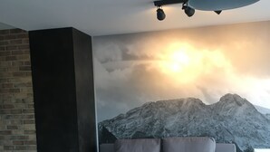 A modern living room with a grey sofa, a black lamp, and a mountain mural on the wall. - Apart Orkana 10 D Zakopane (Zakopane)