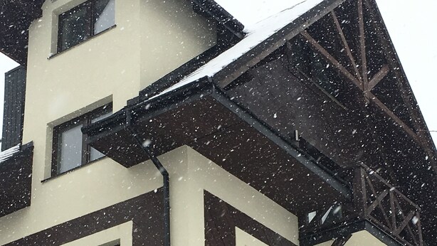 A multi-story building with a modern architectural design, featuring a combination of dark and light-colored panels, multiple windows, and a visible staircase. - Apart Orkana 10 D Zakopane (Zakopane)