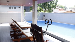 A swimming pool area with lounge chairs and a stationary bike. - Hoang Kim Hotel (Vientiane)