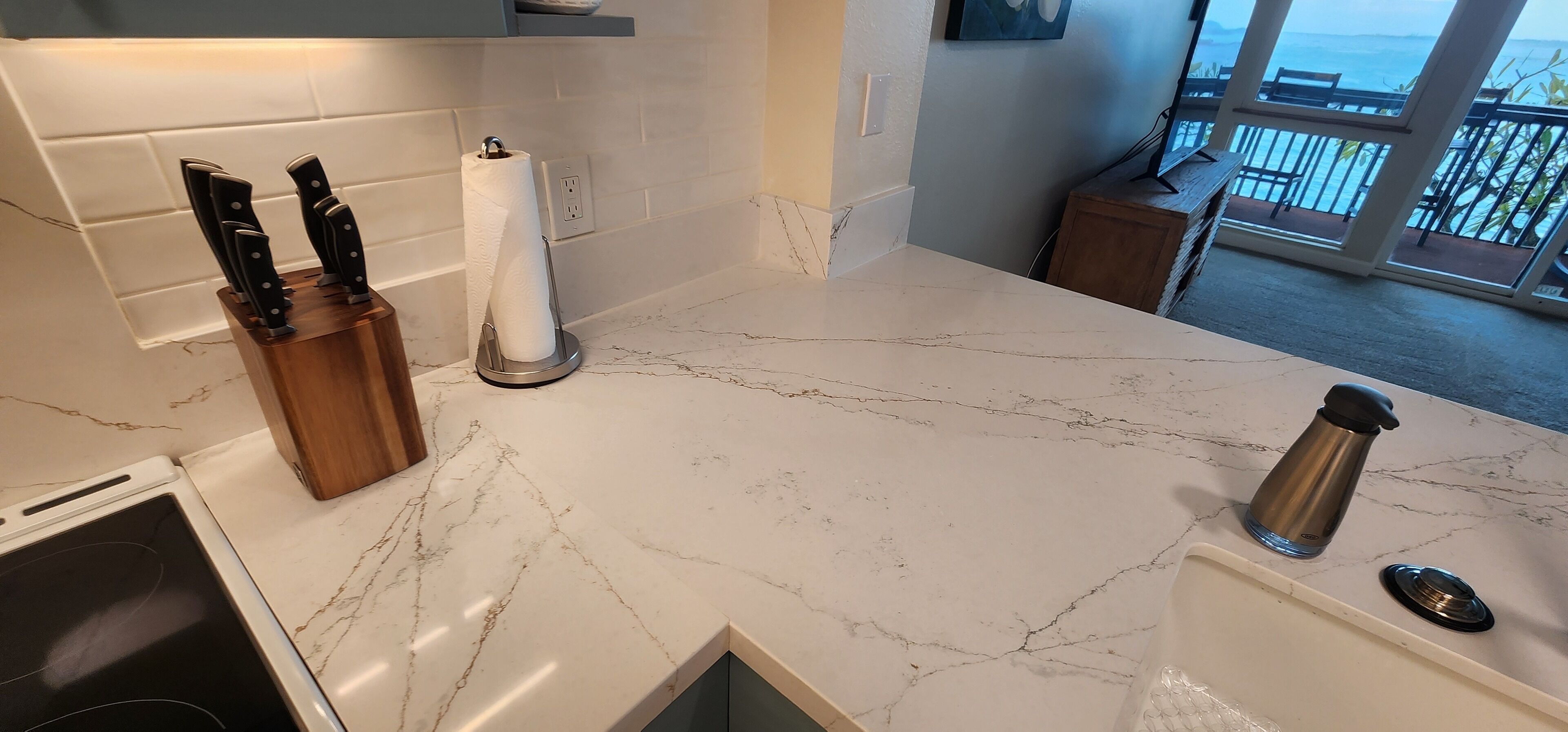A kitchen with marble countertops, a knife block, a paper towel holder, and a coffee maker.