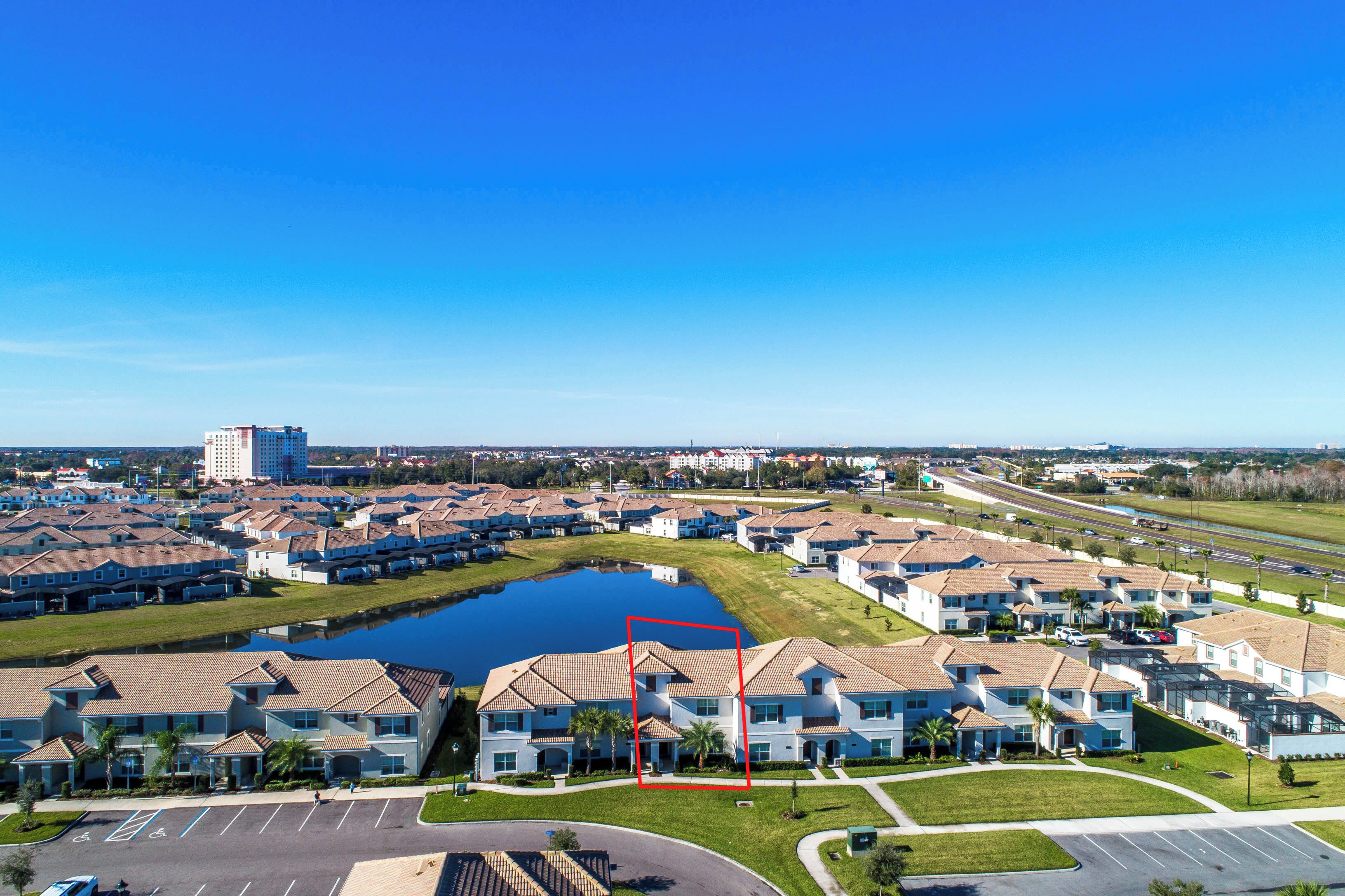 A residential area with a large body of water, a parking lot, and a road.