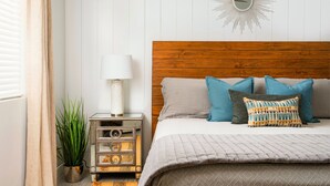 A bedroom with a wooden headboard, a bed with grey bedding and patterned pillows, a bedside lamp, a vintage radio, and a potted plant. - ❤️COMPLETE REMODEL - Old Town Scottsdale, 2BR/2BA En-Suite, Htd Pool, Spa!!! ❤️ (Scottsdale)