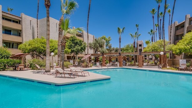 A swimming pool with lounge chairs and palm trees, surrounded by buildings. - ❤️COMPLETE REMODEL - Old Town Scottsdale, 2BR/2BA En-Suite, Htd Pool, Spa!!! ❤️ (Scottsdale)