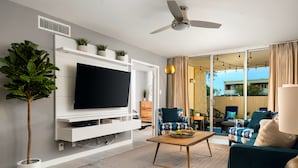 A modern living room with a flat-screen TV, a ceiling fan, and a large window with curtains. - ❤️COMPLETE REMODEL - Old Town Scottsdale, 2BR/2BA En-Suite, Htd Pool, Spa!!! ❤️ (Scottsdale)