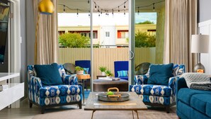 A living room with two patterned armchairs, a coffee table, and a sofa. There is a sliding glass door leading to an outdoor area with a view of buildings and greenery. - ❤️COMPLETE REMODEL - Old Town Scottsdale, 2BR/2BA En-Suite, Htd Pool, Spa!!! ❤️ (Scottsdale)