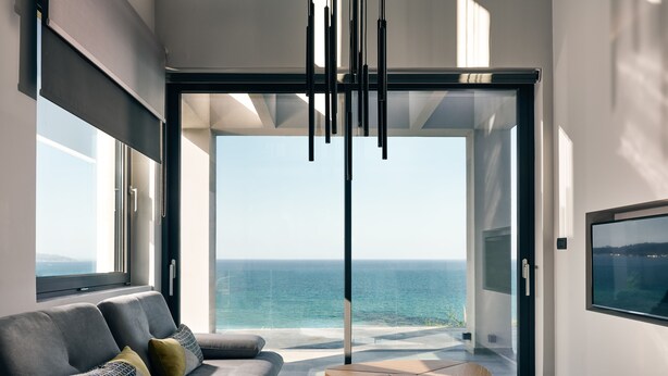 A modern living room with a sofa, a coffee table, and a view of the ocean. - Sueño LUXURY VILLA 180 Iconic Sea View (Zakynthos)