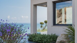 A modern building with a large window overlooking a coastal landscape. - Sueño LUXURY VILLA 180 Iconic Sea View (Zakynthos)