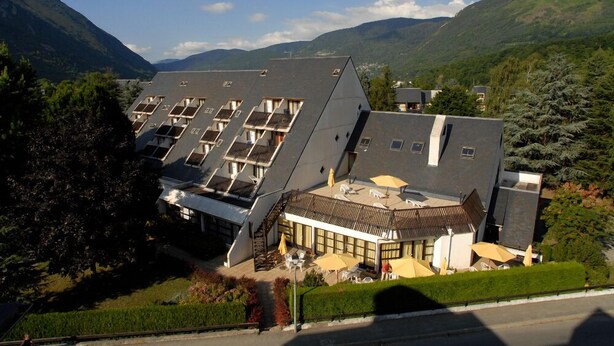 Ein modernes Hotel mit geneigtem Dach, mehreren Balkonen und Außenbereichen zum Sitzen.