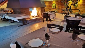 Ein Restaurant mit Kamin aus Stein, gedeckten Tischen und Holzwänden.