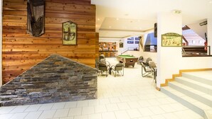 Ein gemütlicher Innenraum mit Holzwänden, einer Wand aus Stein, einem Billardtisch und einer Bar.