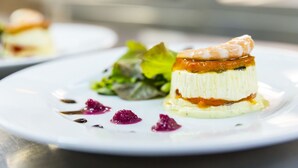 A dessert on a white plate with a side salad and berry garnish.