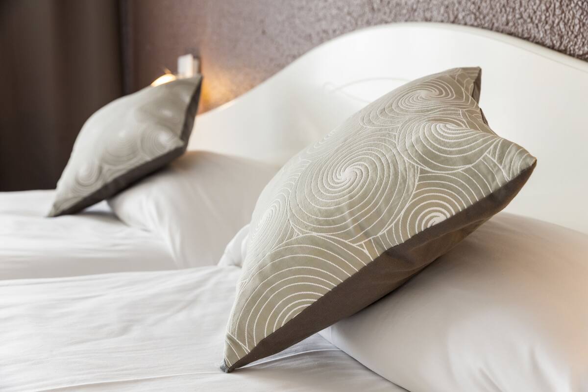 Una cama bien hecha con dos almohadas de diseño en espiral.