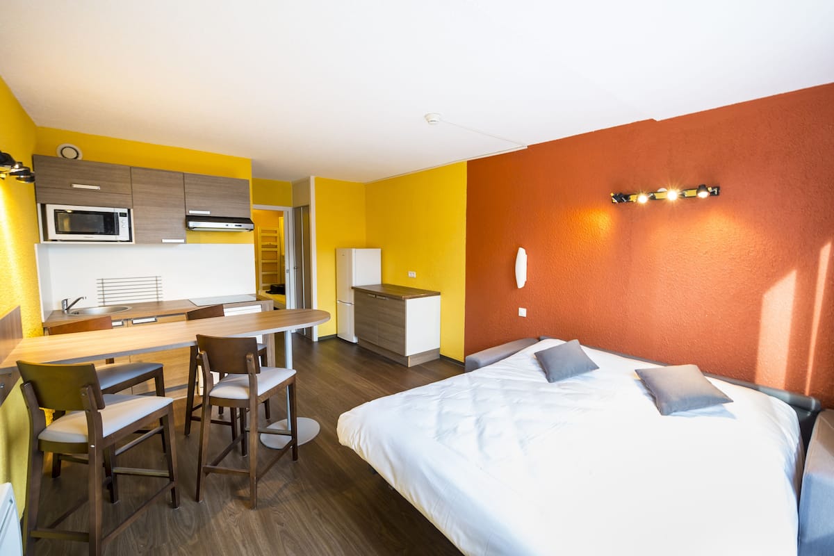 Una habitación de hotel con cama, escritorio y kitchenette.