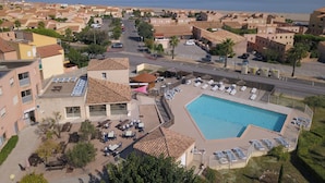 Un complexe hôtelier doté d’une piscine, d’un espace extérieur aménagé et offrant une vue sur la mer.