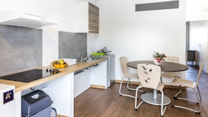 Une cuisine moderne équipée d’une cuisinière intégrée, d’un évier et d’un coin repas avec une table ronde et des chaises.