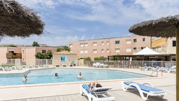 Una piscina al aire libre de temporada, sombrillas