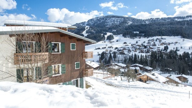 A wooden building with multiple balconies, surrounded by a snowy landscape and a mountain in the background. - Les Essertets - Vacances ULVF (Praz-sur-Arly)