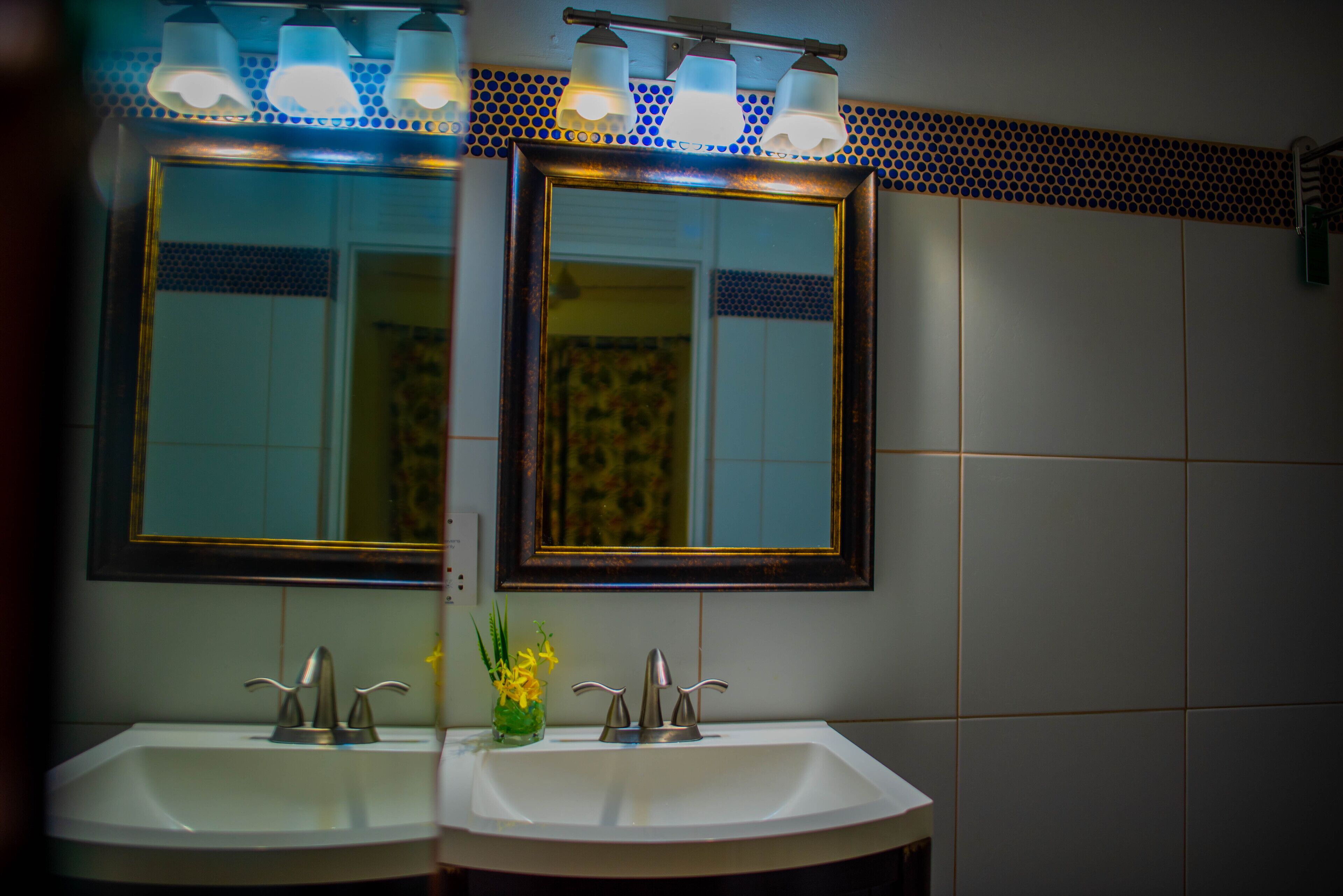 Un baño con dos lavamanos, un espejo y una lámpara sobre el espejo.