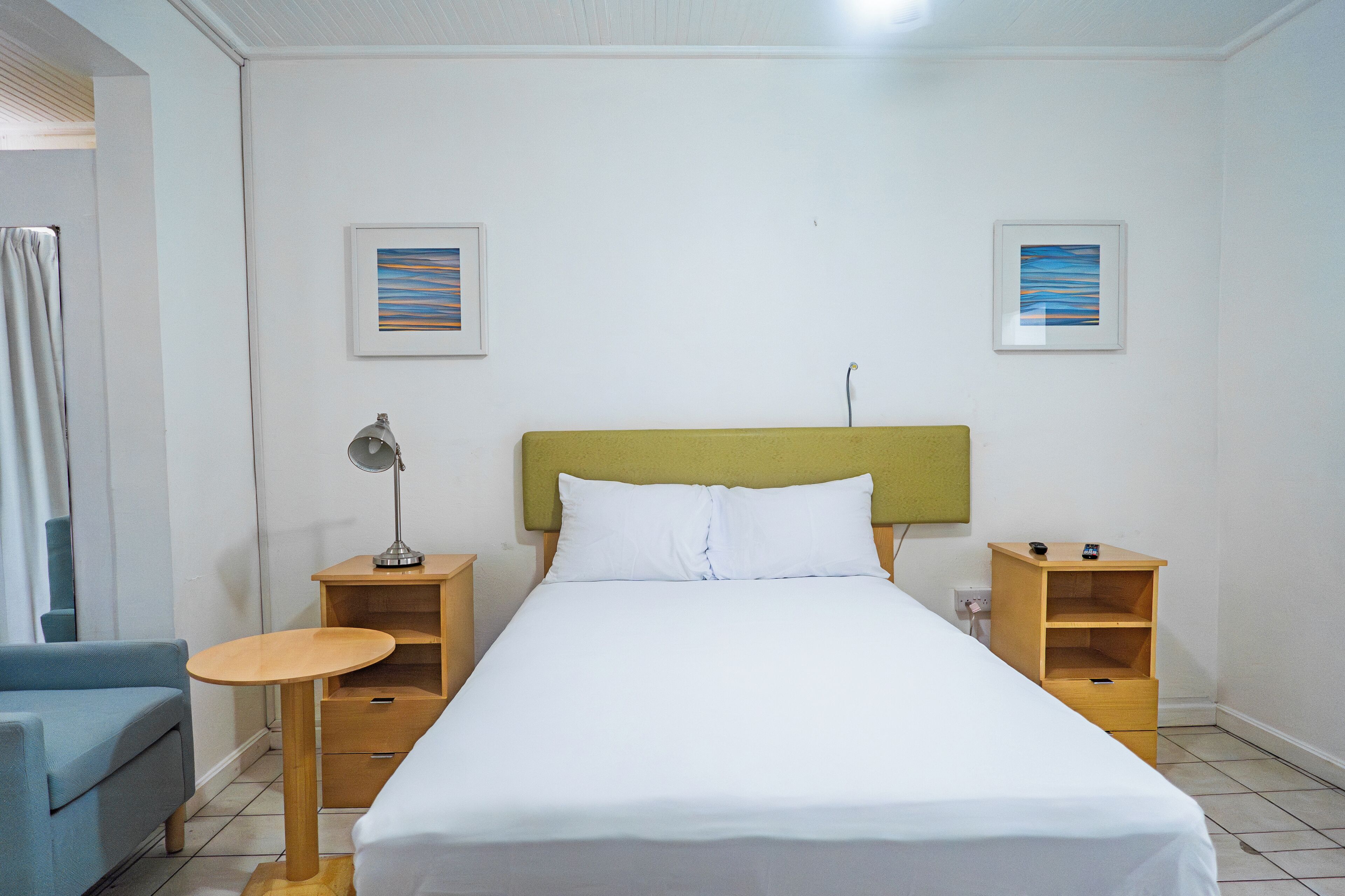 A neatly arranged hotel room with a single bed, a small table, a chair, and two nightstands.