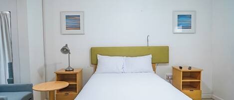 A neatly arranged hotel room with a single bed, a small table, a chair, and two nightstands.