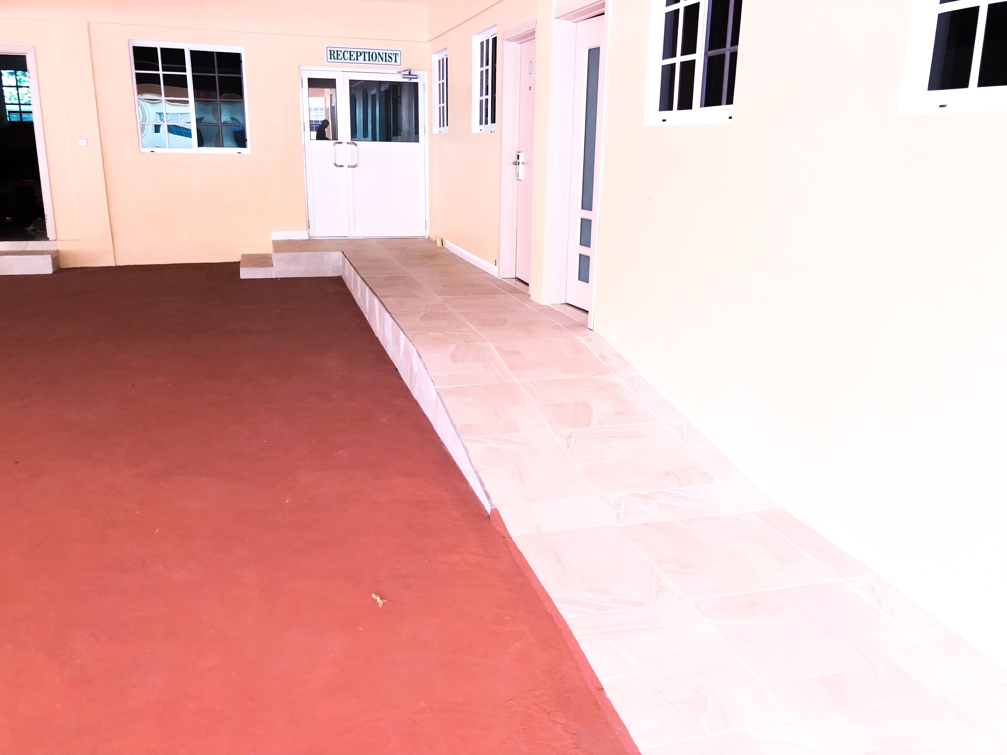 Un espace d’accueil avec un tapis rouge, un comptoir de réception et une pancarte indiquant « RÉCEPTION ».