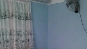 A hotel room with a bed, white linens, a decorative swan pillow, a wall-mounted air conditioner, and a window with patterned curtains. - Hostal Marisol y Marcos (Ciénaga de Zapata)