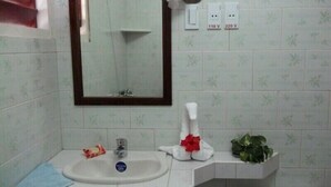 A bathroom with a sink, mirror, and two electrical outlets labeled 110V and 220V. - Hostal Marisol y Marcos (Ciénaga de Zapata)