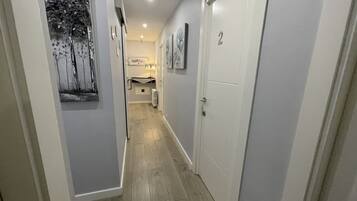 A narrow hallway with a wooden floor, white walls, and a door marked with the number 2.
