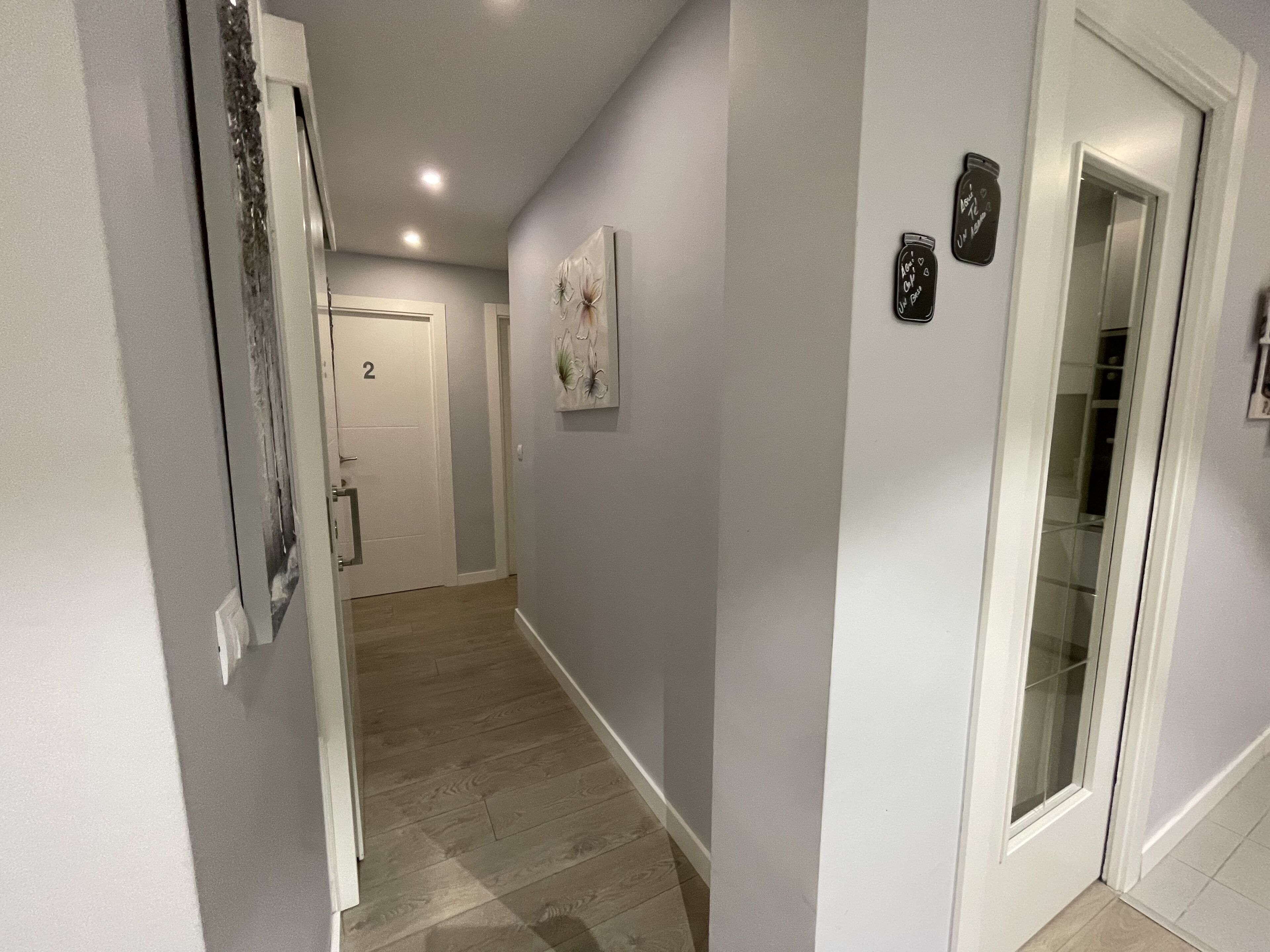 A hallway with a wooden floor, a white door labeled '2', and a glass door with a frosted glass panel.