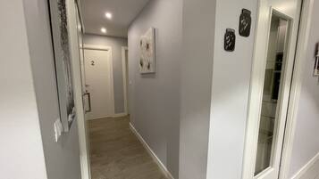 A hallway with a wooden floor, a white door labeled '2', and a glass door with a frosted glass panel.