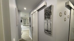 Um corredor com design moderno, apresentando uma porta com arte em metal de árvore, um interruptor de luz e um pequeno objeto decorativo na parede.