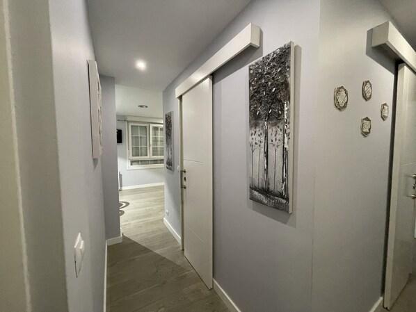 A hallway with a modern design, featuring a door with a metallic tree artwork, a light switch, and a small decorative plate on the wall. - La Rosa Azul Rooms (Ponferrada)