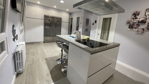 Uma cozinha moderna com uma ilha central, eletrodomésticos de aço inoxidável e forno embutido.