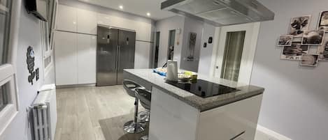 A modern kitchen with a central island, stainless steel appliances, and a built-in oven.