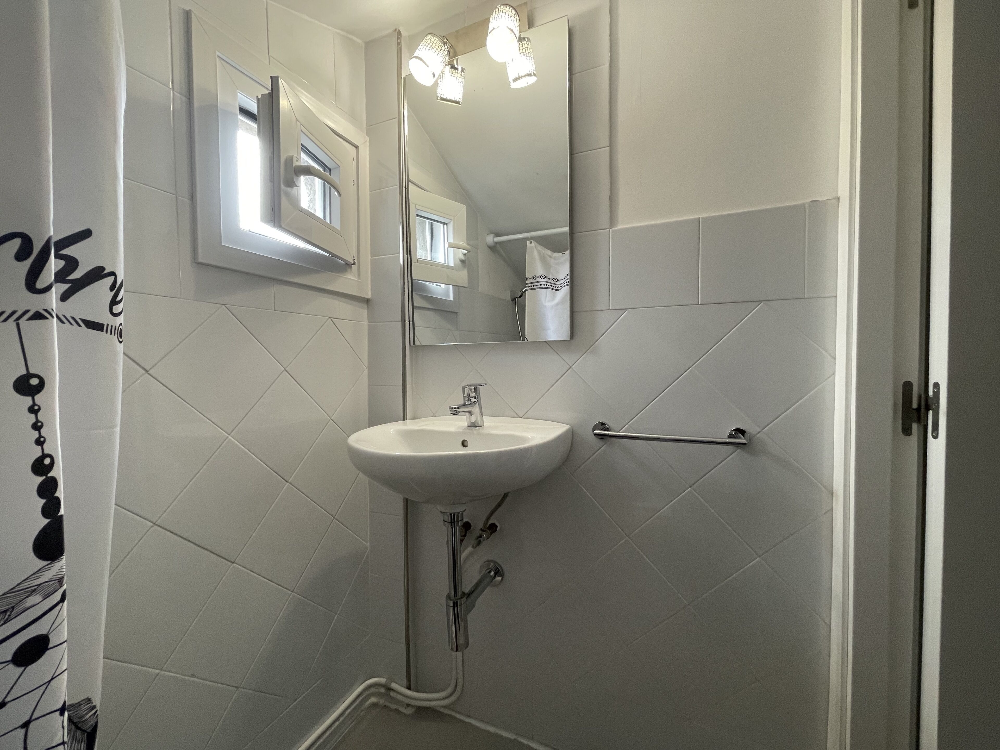 A bathroom with a white sink, a mirror, and a towel rack.