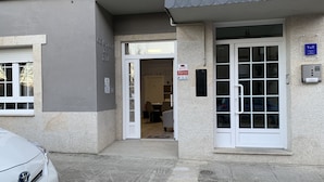 Entrada de um edifício com porta, janela e placa indicando o nome de um negócio.