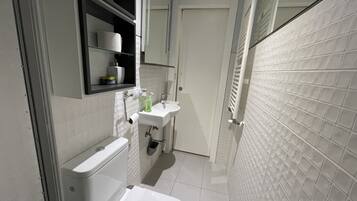 Une salle de bain moderne équipée de toilettes, d’un lavabo et d’une zone douche.
