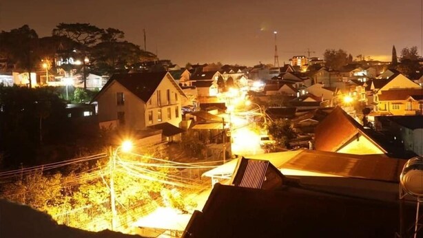 Vista nocturna de una zona residencial densa con edificios iluminados y una torre de agua visible.