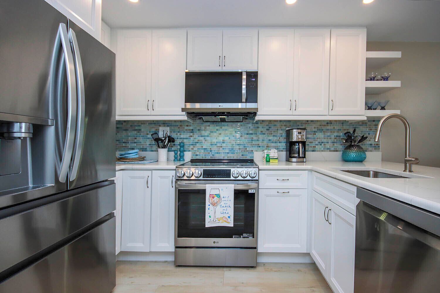 A modern kitchen with white cabinets, stainless steel appliances, and a tiled backsplash.