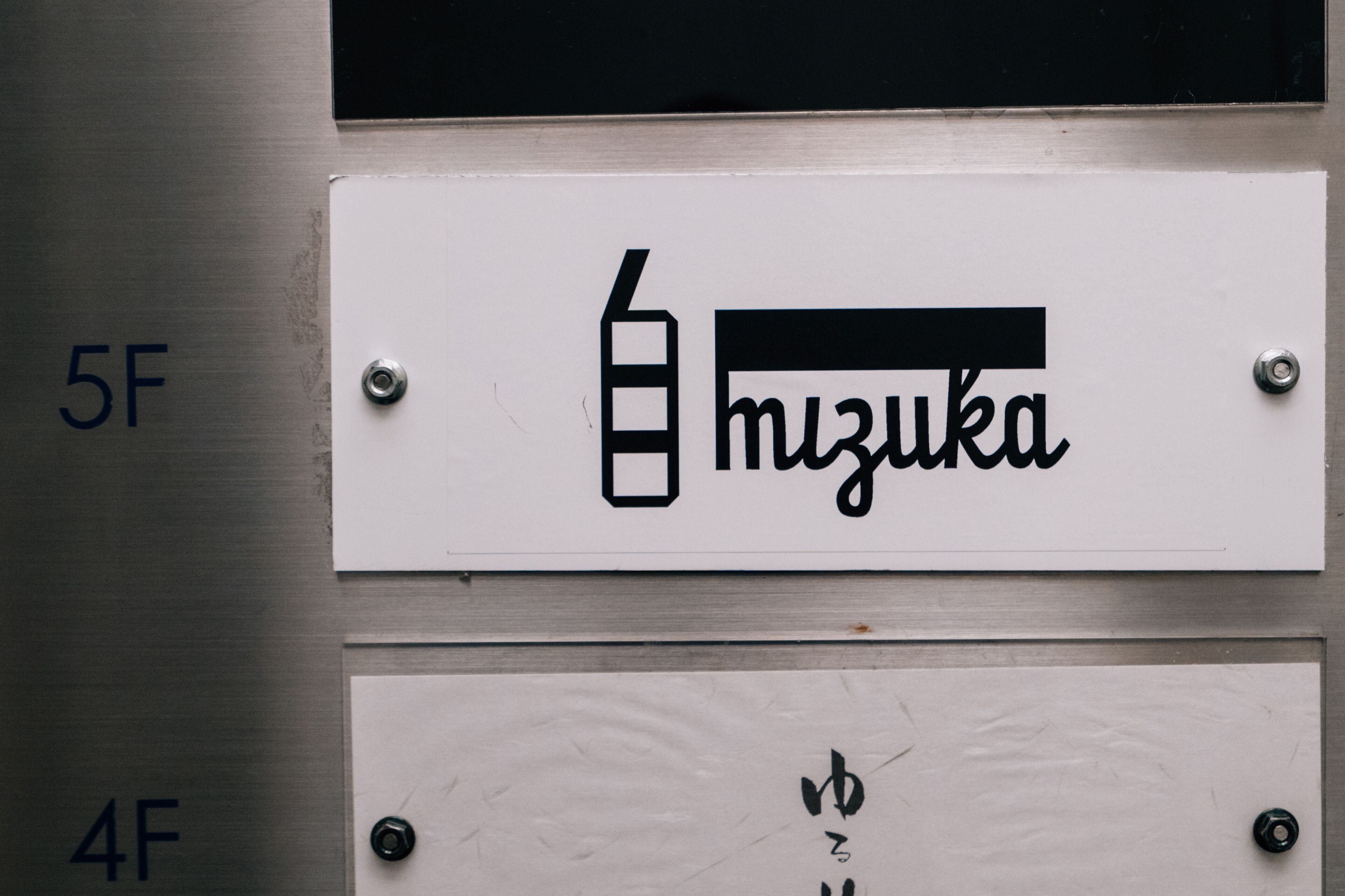 Un letrero de hotel con el nombre 'mizuoka' y un símbolo que indica la presencia de un minibar.