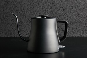 A black teapot with a handle and spout on a dark surface. - mizuka Nakasu 1 - unmanned hotel - (Fukuoka)
