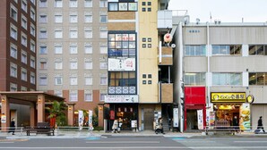 A multi-story building with various commercial establishments on the ground floor, including a restaurant with a prominent yellow sign. - mizuka Nakasu 1 - unmanned hotel - (Fukuoka)