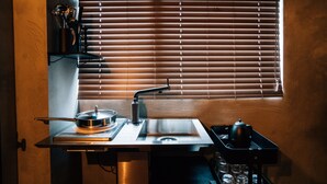 A compact kitchen with a built-in stove, sink, and a window with blinds. - mizuka Nakasu 1 - unmanned hotel - (Fukuoka)